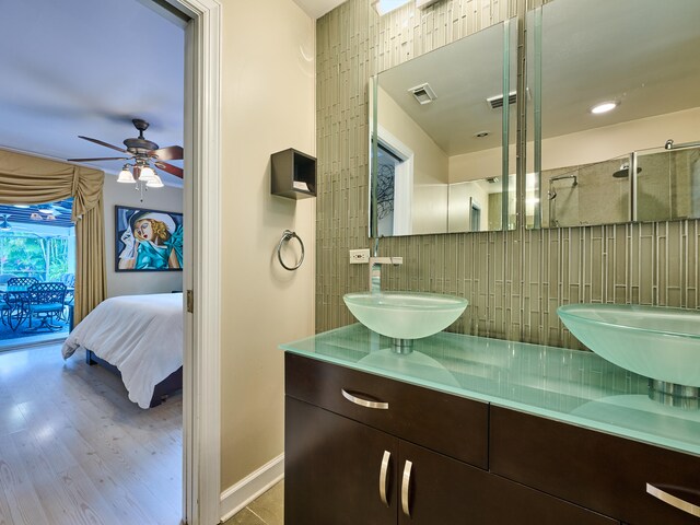 bathroom featuring vanity, hardwood / wood-style flooring, ceiling fan, and tasteful backsplash