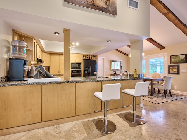 kitchen with black appliances, lofted ceiling with beams, kitchen peninsula, dark stone counters, and light brown cabinets