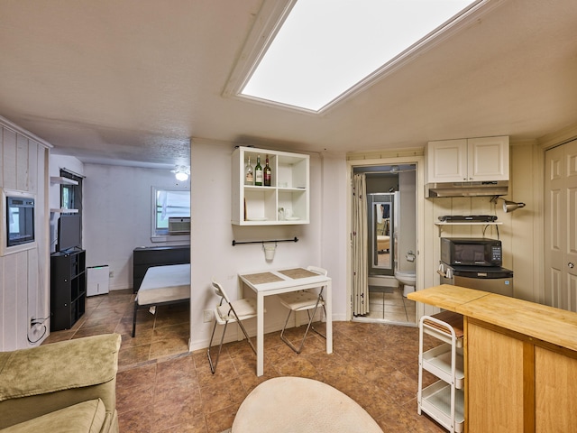 18238 128th Trl N, Jupiter, FL 33478 - kitchen with black microwave, under cabinet range hood, butcher block counters, white cabinets, and baseboards