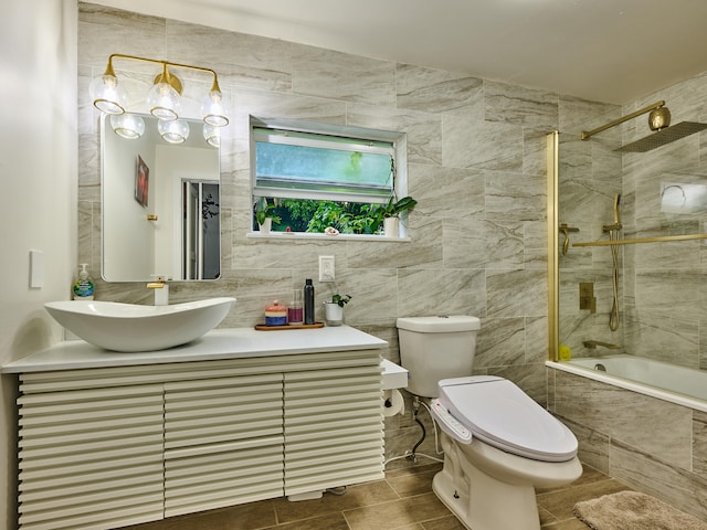 full bathroom featuring toilet, tiled shower / bath, tile walls, and vanity