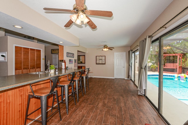 kitchen featuring ceiling fan, dark hardwood / wood-style floors, a breakfast bar, and sink