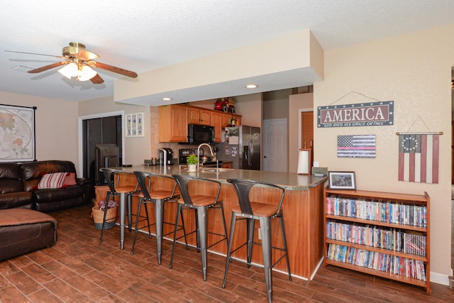 kitchen featuring stainless steel refrigerator with ice dispenser, a breakfast bar, kitchen peninsula, and ceiling fan