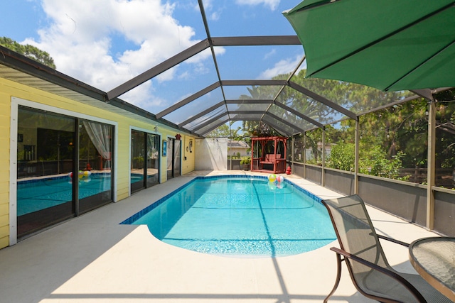 view of swimming pool with glass enclosure and a patio