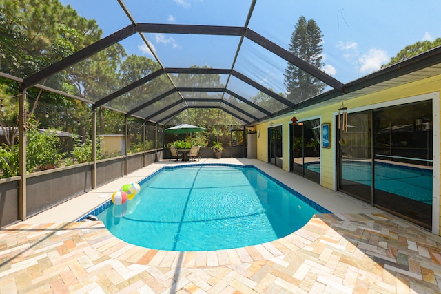 view of swimming pool with glass enclosure and a patio