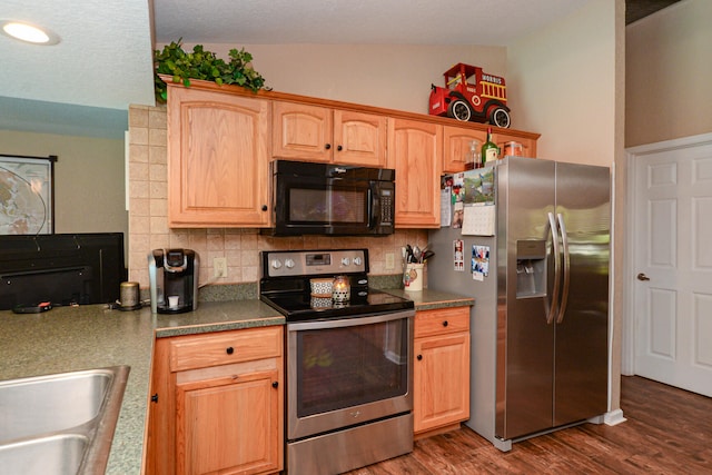 kitchen featuring appliances with stainless steel finishes, lofted ceiling, dark hardwood / wood-style flooring, sink, and backsplash