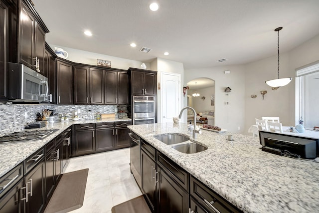 kitchen featuring stainless steel appliances, decorative light fixtures, light stone countertops, decorative backsplash, and sink