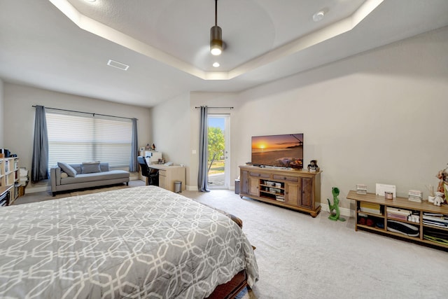 carpeted bedroom featuring access to exterior and a tray ceiling