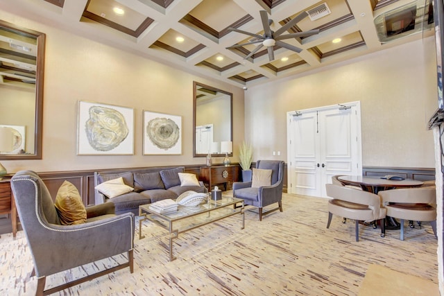 living room with a towering ceiling, ceiling fan, beam ceiling, and coffered ceiling