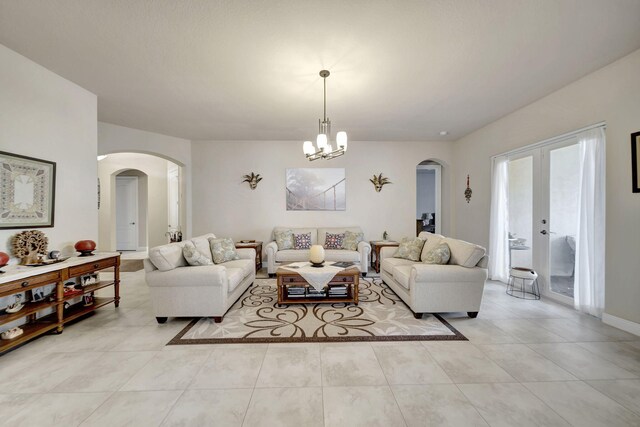 tiled living room featuring a chandelier and french doors