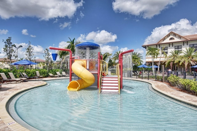 view of swimming pool with a water slide, a playground, and pool water feature