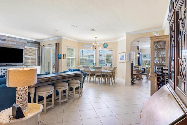 interior space with an inviting chandelier, crown molding, pendant lighting, a textured ceiling, and light tile patterned flooring