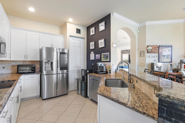 kitchen featuring dark stone counters, white cabinets, sink, ornamental molding, and appliances with stainless steel finishes