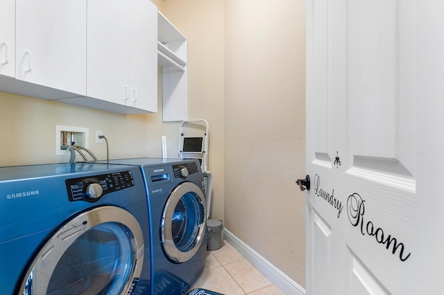 washroom with cabinets, light tile patterned floors, and washer and clothes dryer