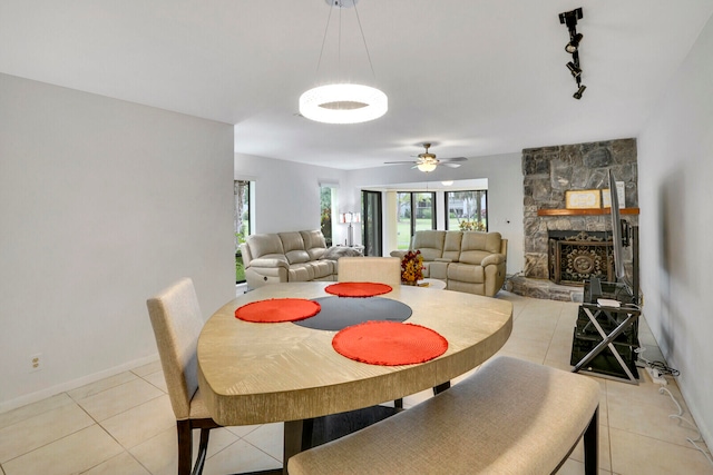 dining area featuring a wealth of natural light, a fireplace, light tile floors, and rail lighting