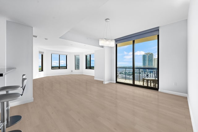 living room with light hardwood / wood-style floors, an inviting chandelier, and floor to ceiling windows