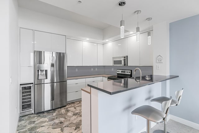 kitchen with kitchen peninsula, appliances with stainless steel finishes, and white cabinetry