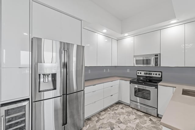 kitchen with white cabinets, appliances with stainless steel finishes, and beverage cooler