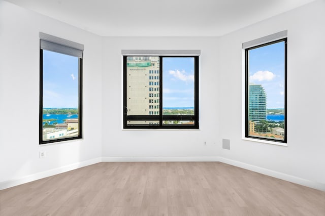 unfurnished room featuring light hardwood / wood-style floors and a water view