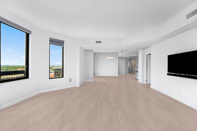 unfurnished living room with light hardwood / wood-style flooring and a chandelier