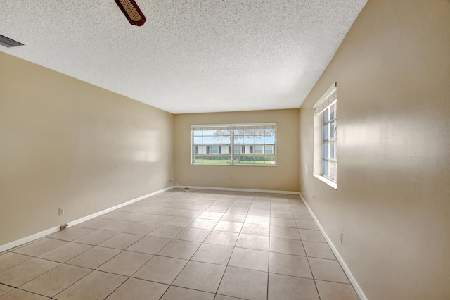 empty room with ceiling fan, light tile patterned flooring, and a textured ceiling