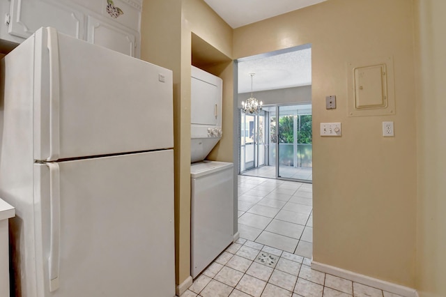 kitchen featuring white cabinets, light tile patterned floors, white refrigerator, and stacked washer / dryer