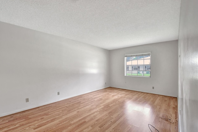 unfurnished room featuring light wood-type flooring and a textured ceiling