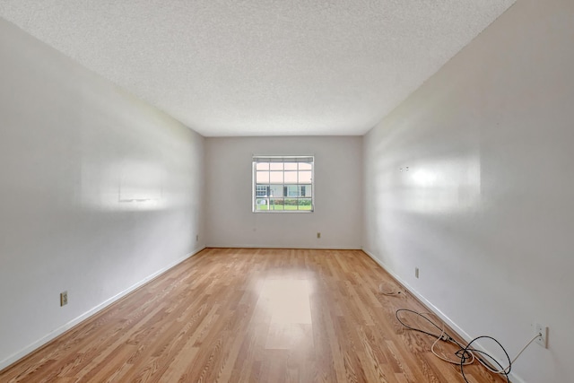 unfurnished room featuring a textured ceiling and light wood-type flooring