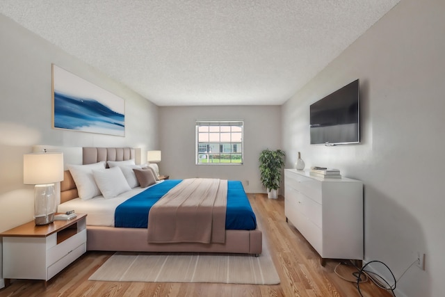 bedroom with a textured ceiling and light wood-type flooring