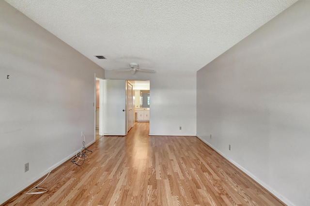 unfurnished room with a textured ceiling and light wood-type flooring