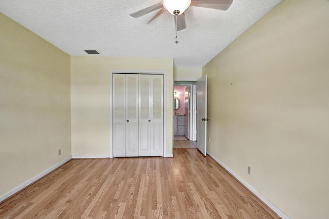 unfurnished bedroom featuring ceiling fan, light wood-type flooring, a textured ceiling, and a closet