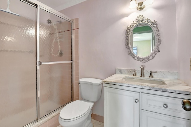 bathroom featuring tile patterned flooring, vanity, toilet, and a shower with shower door