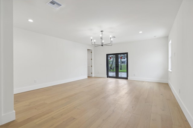 empty room with a chandelier, french doors, and light wood-type flooring