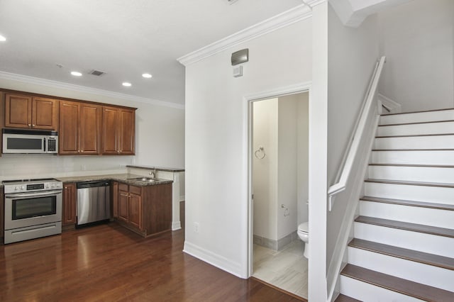 kitchen featuring dark hardwood / wood-style flooring, ornamental molding, appliances with stainless steel finishes, and tasteful backsplash