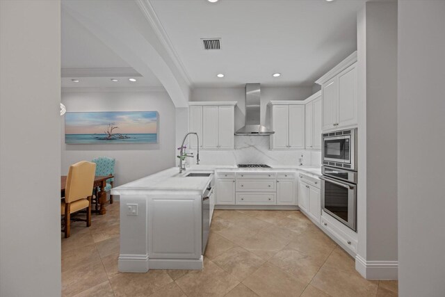 kitchen with wall chimney range hood, appliances with stainless steel finishes, sink, tasteful backsplash, and light tile flooring