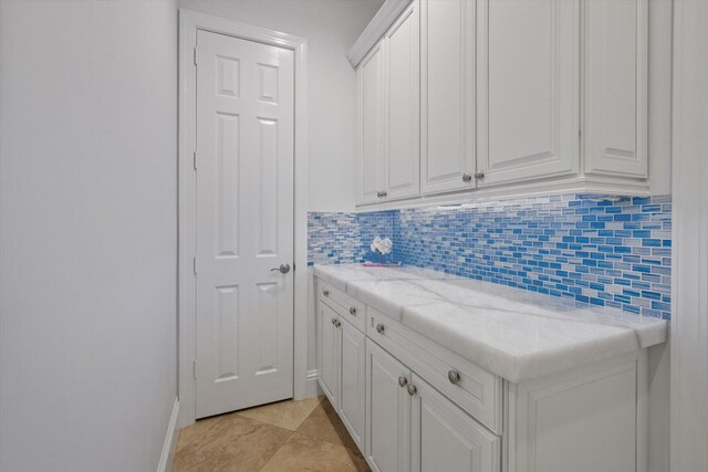 kitchen with white cabinetry, tasteful backsplash, light tile flooring, and light stone counters