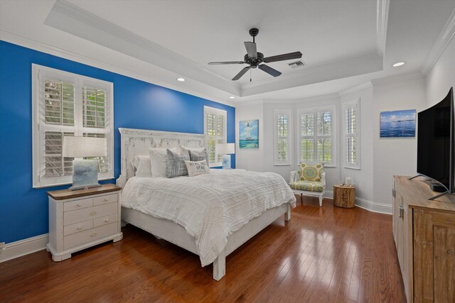 bedroom with dark wood-type flooring, a tray ceiling, and multiple windows