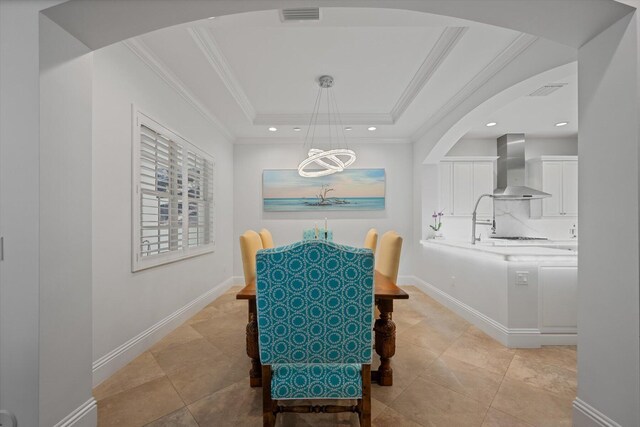 tiled dining space with ornamental molding and a raised ceiling