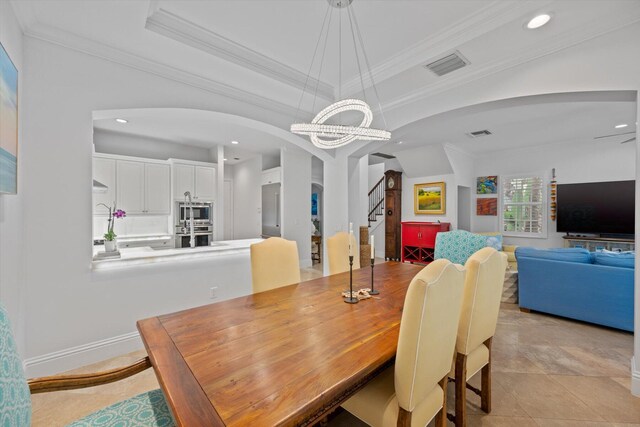 tiled dining space with a tray ceiling, crown molding, and a chandelier