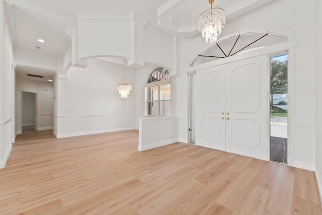 entrance foyer featuring light hardwood / wood-style flooring, an inviting chandelier, and beam ceiling