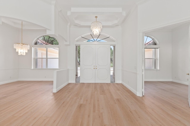 entrance foyer featuring a wealth of natural light, a high ceiling, an inviting chandelier, and light wood-type flooring