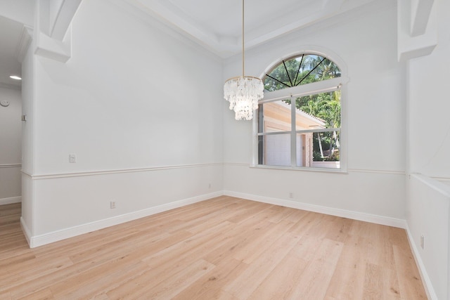 empty room with crown molding, light hardwood / wood-style flooring, and a notable chandelier