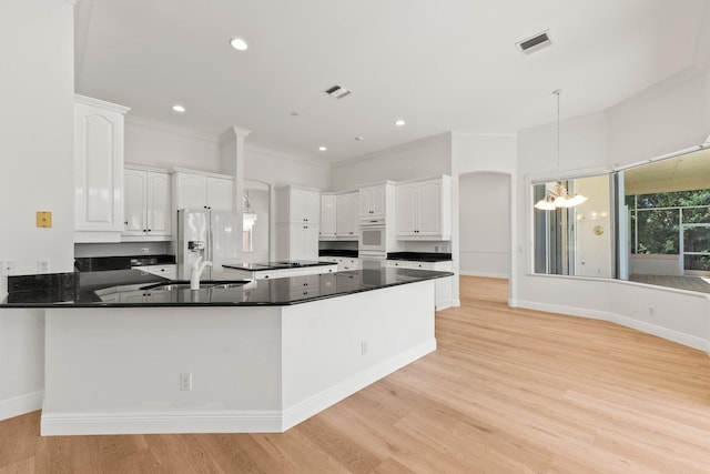 kitchen with pendant lighting, an inviting chandelier, light wood-type flooring, and white cabinets