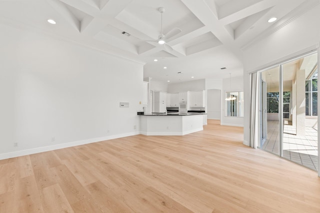 unfurnished living room with light wood-type flooring, coffered ceiling, beamed ceiling, crown molding, and ceiling fan