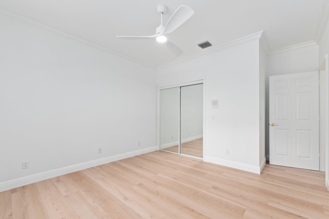 unfurnished bedroom with light wood-type flooring, ornamental molding, ceiling fan, and a closet