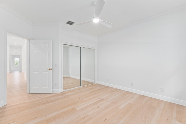 unfurnished bedroom with light wood-type flooring, a closet, ceiling fan, and crown molding