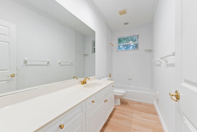 full bathroom with vanity, wood-type flooring, toilet, ornamental molding, and tiled shower / bath