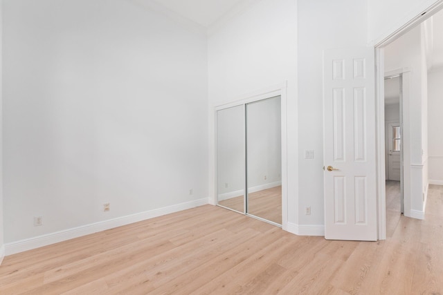 unfurnished bedroom with light hardwood / wood-style flooring, ornamental molding, and a closet