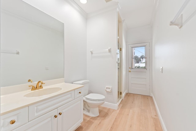 bathroom featuring toilet, ornamental molding, vanity, wood-type flooring, and a shower with shower door