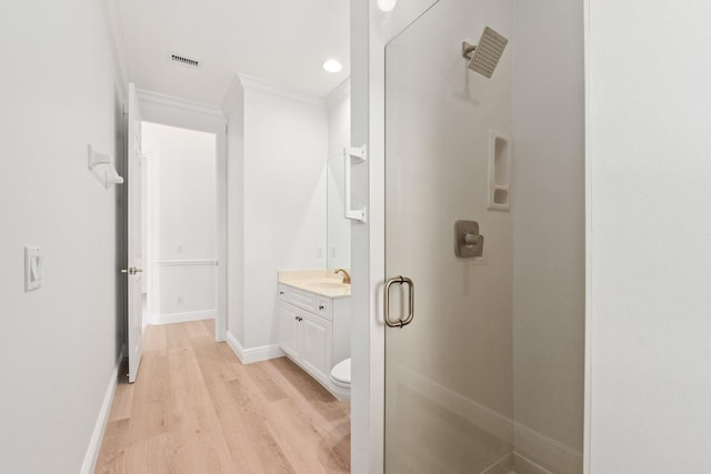 bathroom with toilet, hardwood / wood-style flooring, ornamental molding, and vanity