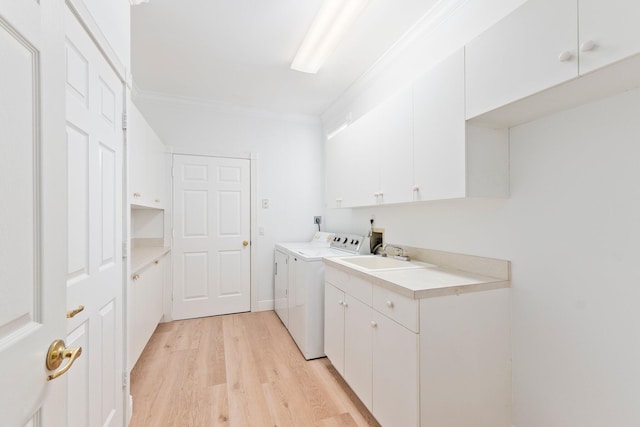 laundry room featuring cabinets, light hardwood / wood-style floors, washing machine and clothes dryer, ornamental molding, and sink